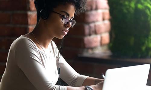 Female student in headphones using laptop